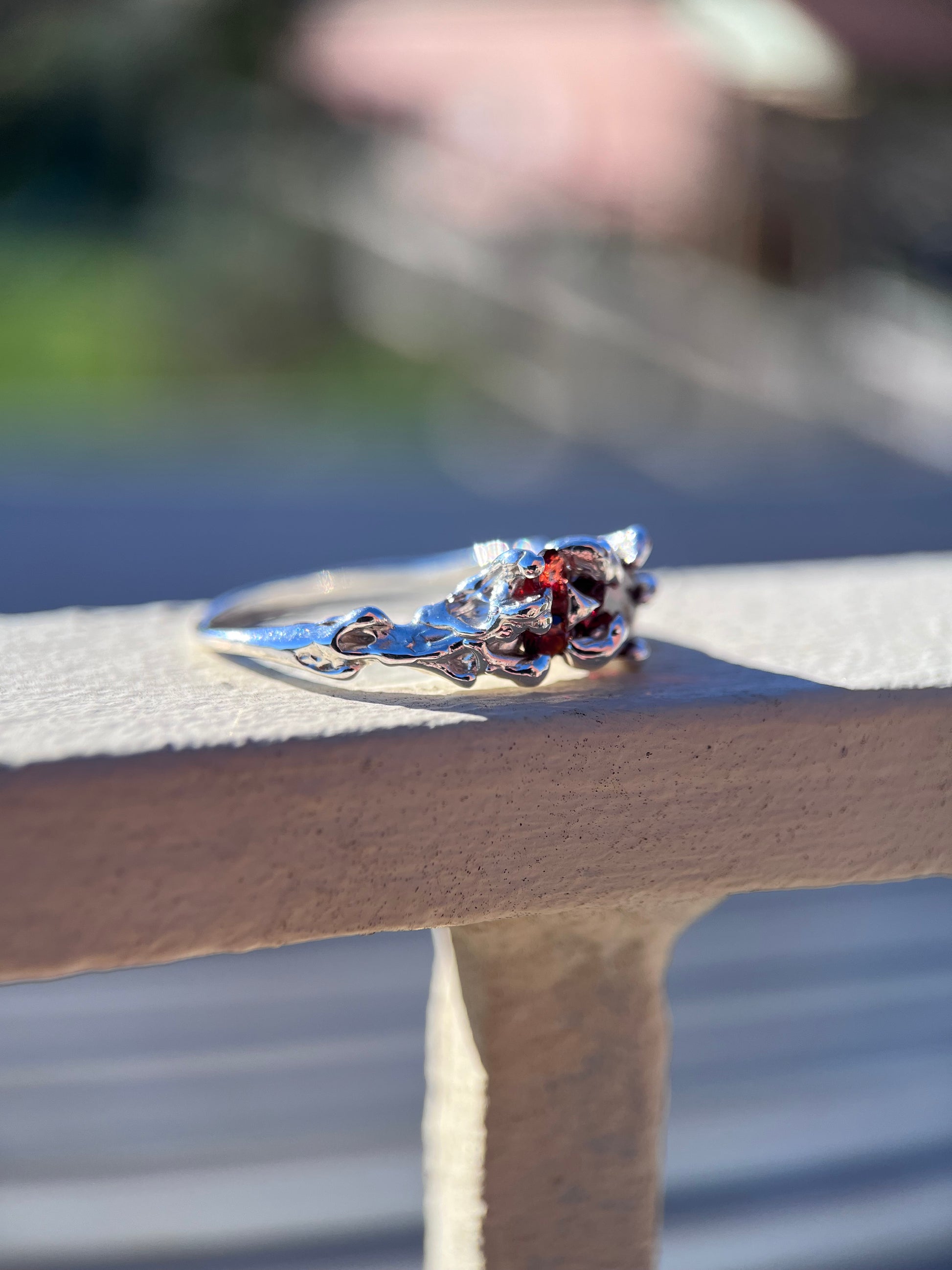 Ethereal silver ring with three wine red Garnets and a vine like texture on the ring face