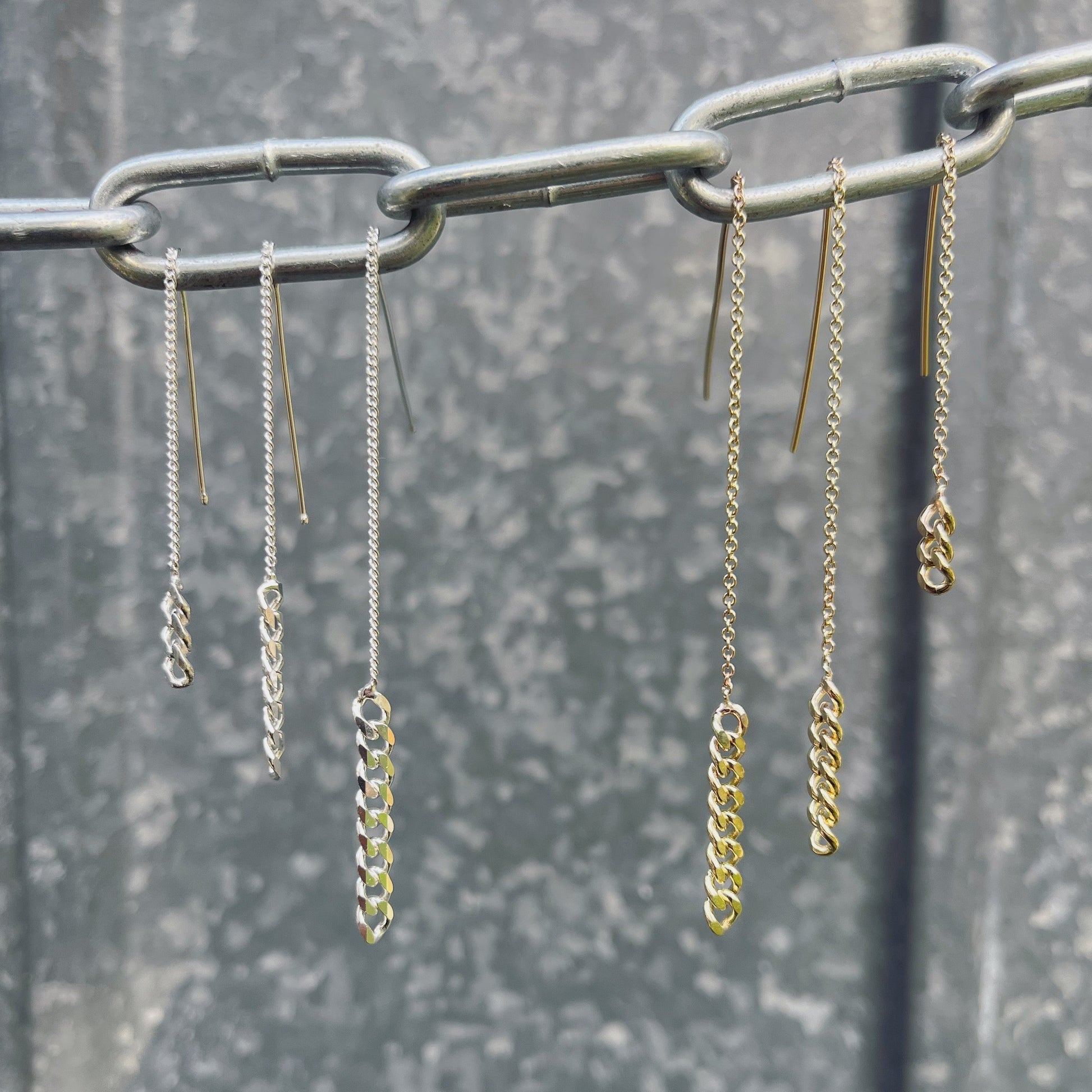 Six Gold and Silver chain pull through earrings hanging off a large chain in three different sizes