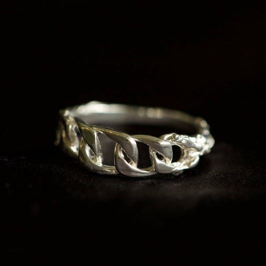 Chain ring with organic texture on black velvety background 