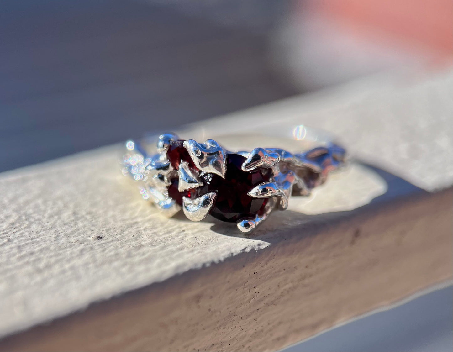 Ethereal silver ring with three wine red Garnets and a vine like texture on the ring face