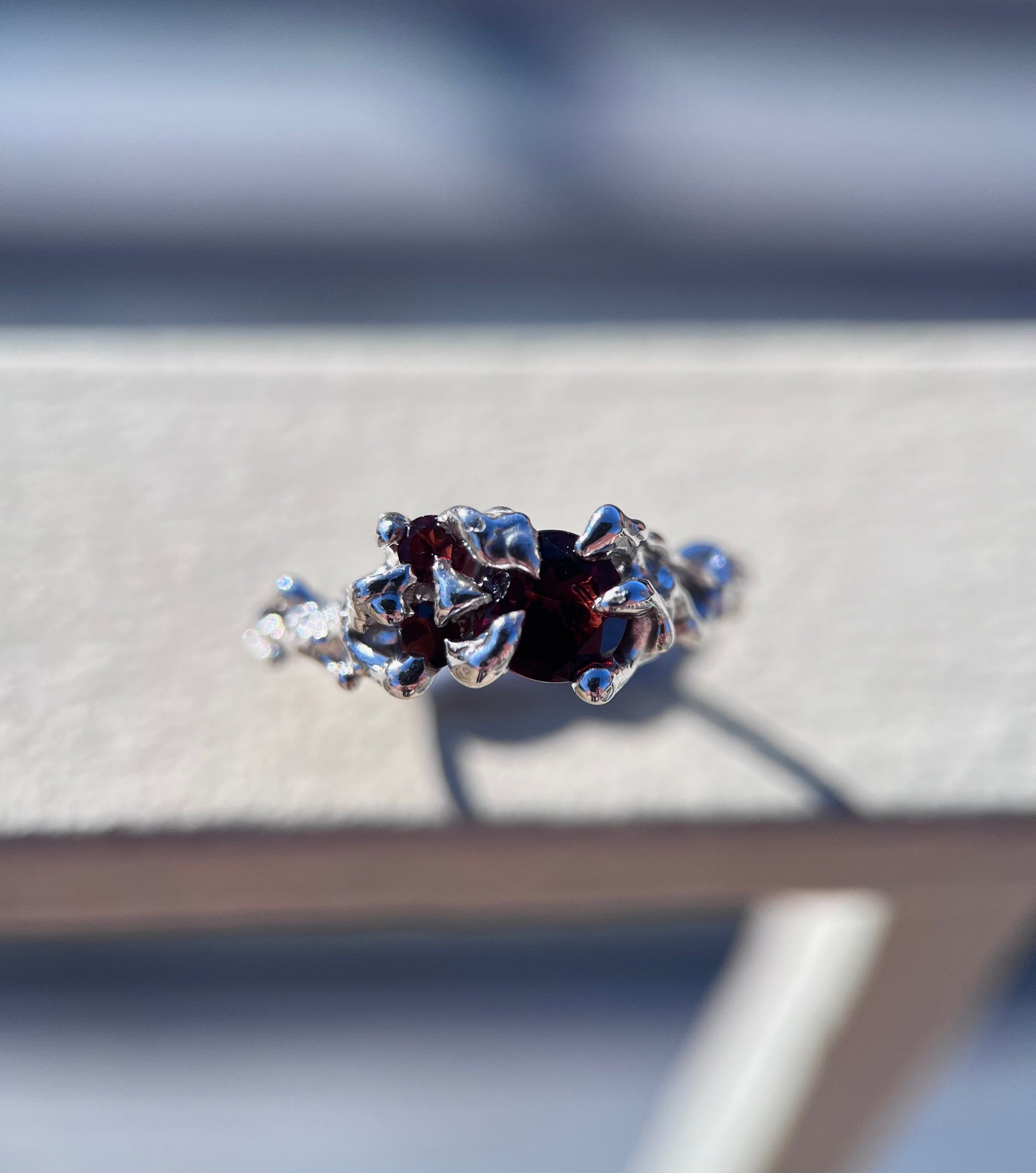 Ethereal silver ring with three wine red Garnets and a vine like texture on the ring face