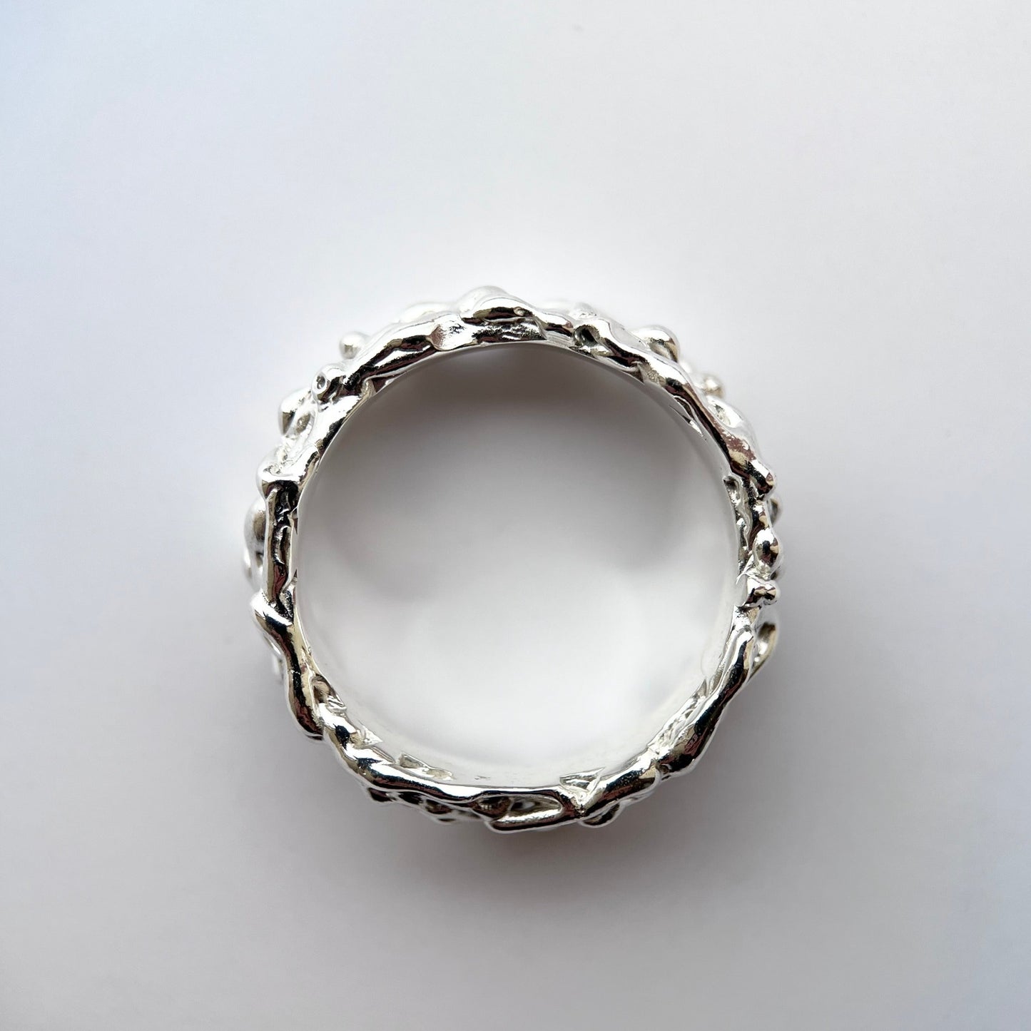 Silver thick band with organic texture on a grey background