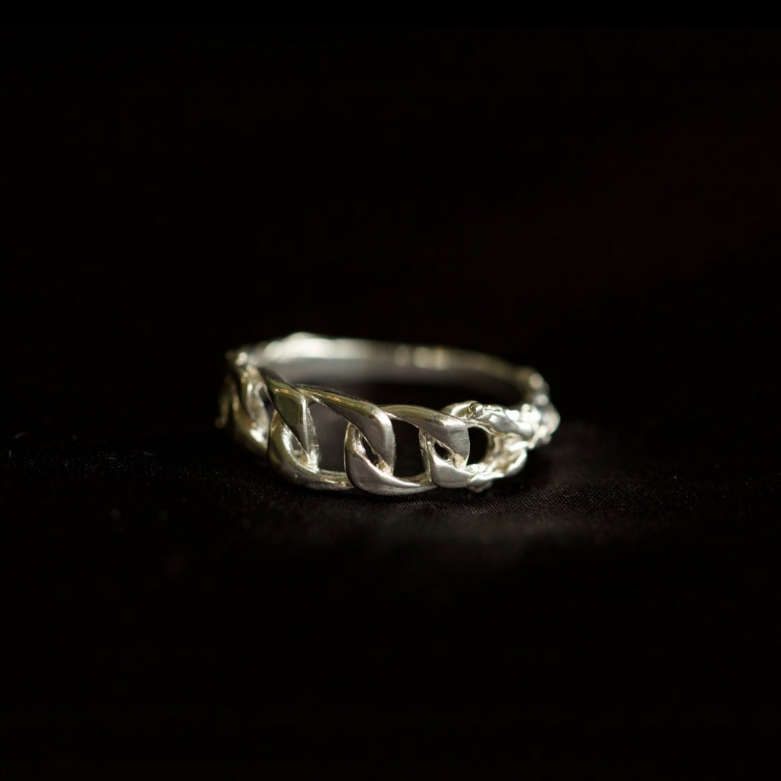 Chain ring with organic texture on black velvety background 