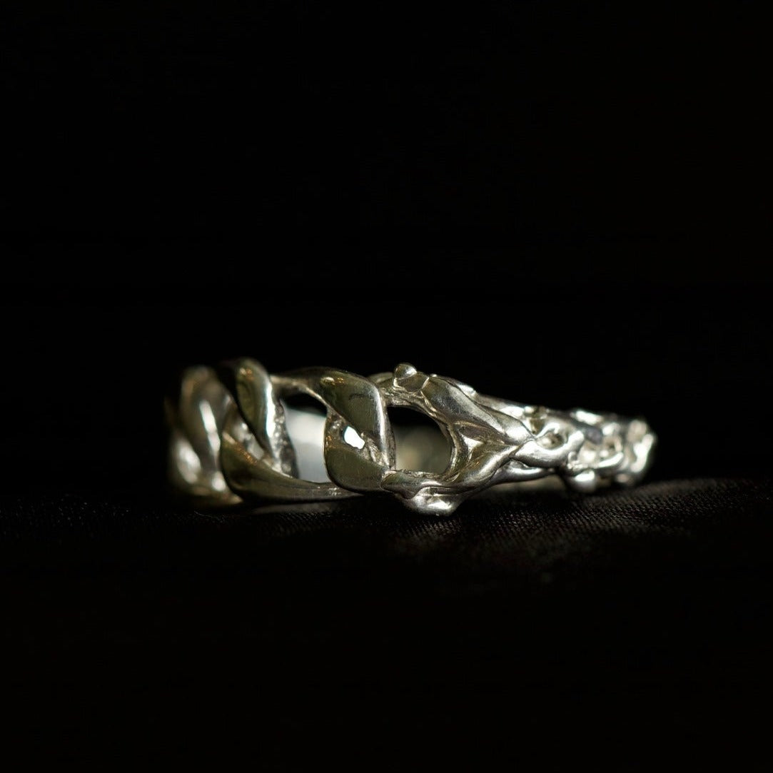 Chain ring with organic texture on black velvety background 