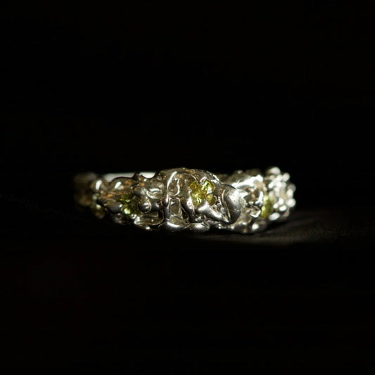 Photo of silver ring with six yellow parti sapphires with and organic texture on a black background